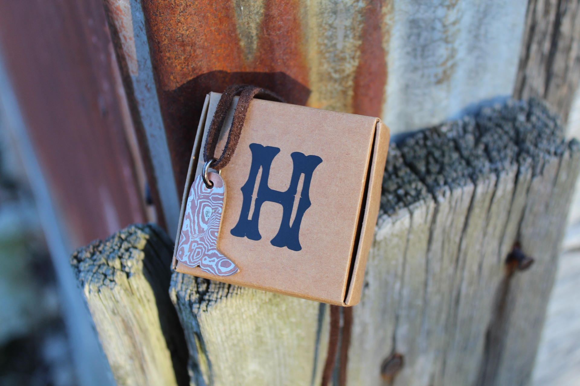 Damascus boot pendant hanging beside a Big H branded box