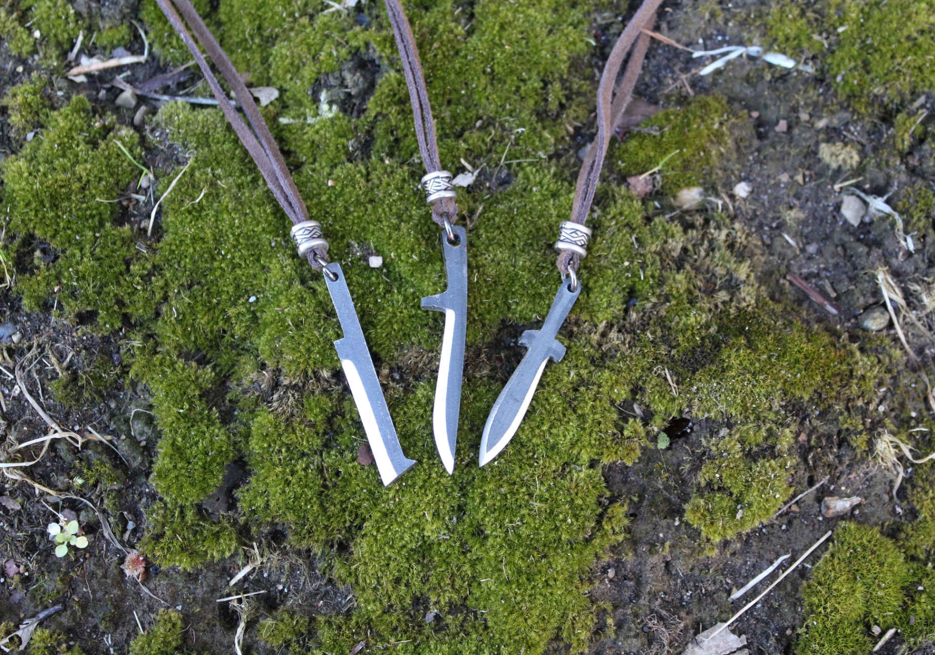 Three knife pendants resting on green moss