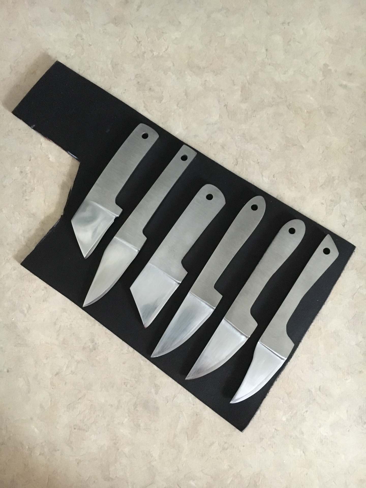 Set of six polished knife blanks laid out on black leather